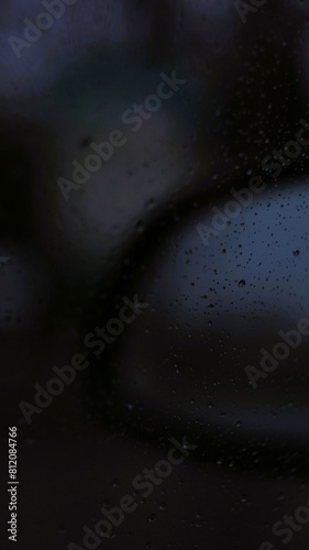 rainy car mirror with water drops, blur dark
