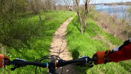 Two cyclists riding on a forest trail on mountain bikes. First-person view.