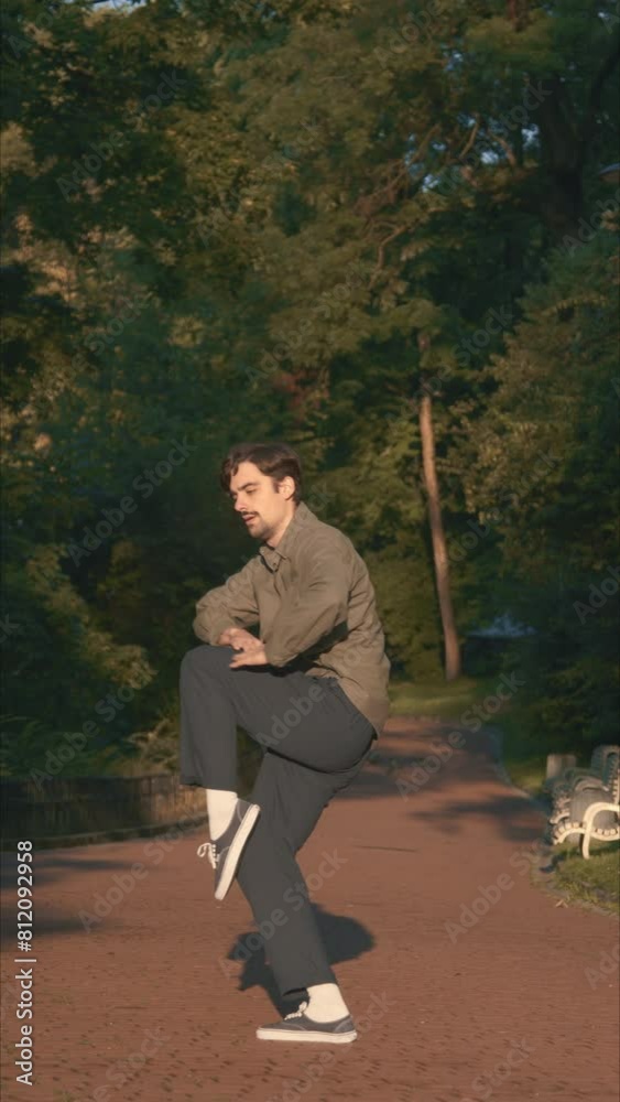 A Dancer Performs Contemporary: Improvisation At Sunset In The Park 4k Video. Quiet man uses his whole body to dance. The park is flooded with soft light of green colors. A shadow is visible near guy.