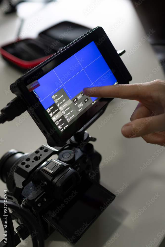 Imagen vertical de mano configurando monitor para filmar sobre cámara en jaula Imagen vertical de mano configurando monitor para filmar sobre cámara en jaula