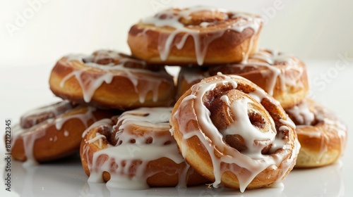 A stack of cinnamon rolls, icing perfectly drizzled, against white