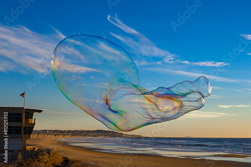 2024-01-28 A LARGE SOAP BUBBLE WITH ABSTRACT TONES IN IT FLOATING OVER A SANDY BEACH IN MISSION BEACH CALIFORNIA WITH A BLURRED BACKGROUND AND A NICE SKY NEAR SAN DIEGO CALIFORNIA