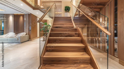 Chic luxury home interior featuring a wooden staircase with glass railings leading to a sophisticated upper level