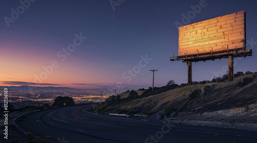 Enormous roadside billboard on a hill overlooking a sleeping city under a clear night sky.