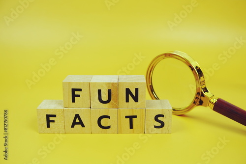 Funfacts with wooden blocks alphabet letters and Magnifying glass on yellow background photo