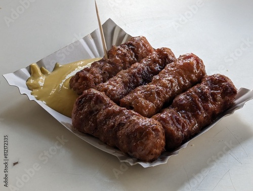 Obraz na płótnie Mici cu mustar and a toothpick on a paper plate. Traditional romanian fast food. w salonie