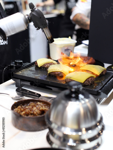 chef fundiendo queso en las hamburguesas con un soplete de cocina photo