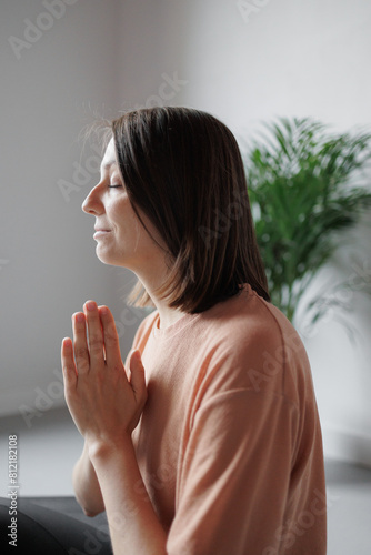 Caucasian woman meditates in lotus namaste pose with her eyes closed at home. Spiritual and physical practices for mental health. Sports and recreation. happy Person trains, strength exercises