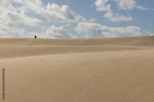 People walking up sand dunes on a bright sunny day in the desert