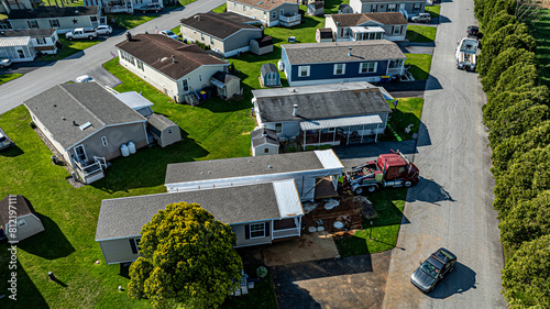 An Aerial View of a Manufactured, Mobile, Prefab Double Wide Home Being Installed in a Lot in a Park photo