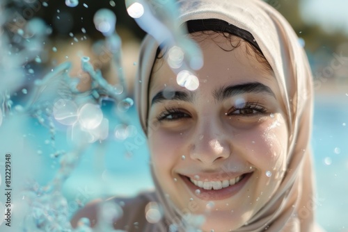 Close-up of a girl in a hijab with water droplets  capturing a moment of joy in the water