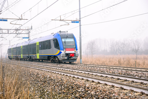 Commuter train speeding through the countryside on a foggy winter morning