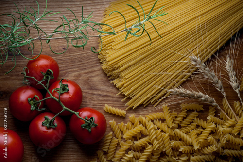 Italy food pasta still life. Spaghetti, fusilli, tomatoes, rosemary on wooden table