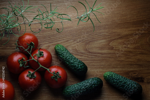 Tomatoes, cucumbers, rosemary branch on wooden table