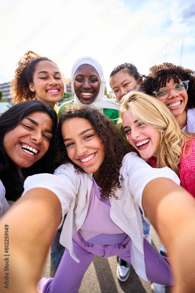 Obraz premium Vertical group of young smiling multiracial only women taking selfie photo looking at camera outdoor. Cheerful beautiful female friends with positive face emotions. Girls Power diversity and community