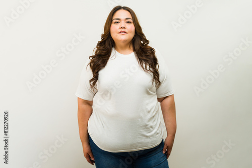 T-shirt mockup of a plus-size woman standing proudly in a studio, wearing a white shirt © AntonioDiaz