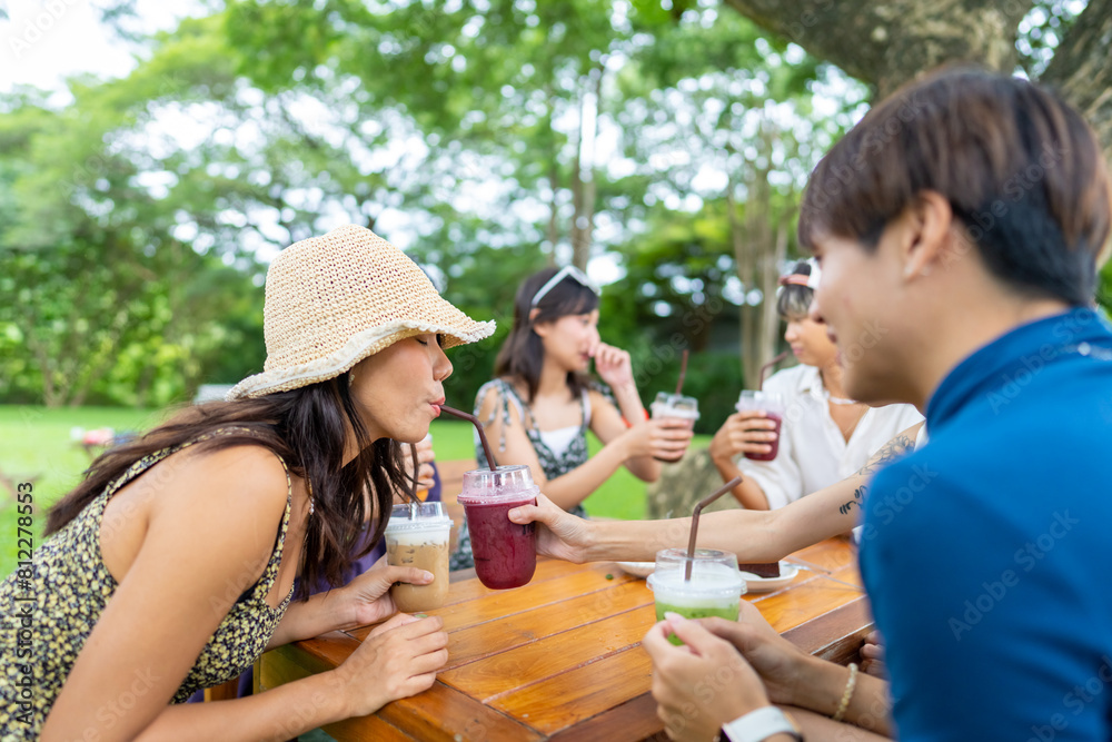 Obraz premium Happy young Asian man and woman enjoy outdoor lifestyle travel nature and cafe on summer holiday vacation. Generation z people friends eating cake and drinking coffee together at outdoor restaurant.