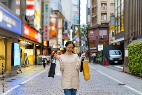 Photography Happy Asian woman holding shopping bag walking at Shibuya district, Tokyo, Japan in evening