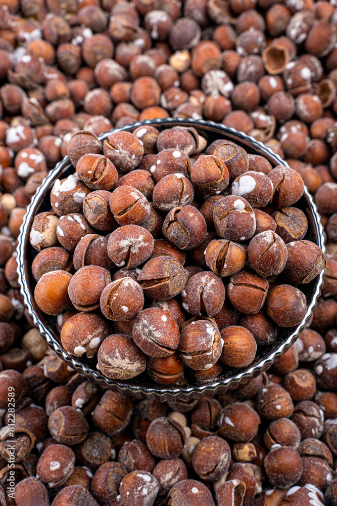 Salted Hazelnuts in Black Bowl Over Scattered Nuts Background, Close-up of salted hazelnuts in a decorative black bowl, set against a backdrop of scattered nuts. Salted Hazelnuts in Black Bowl Over Scattered Nuts Background, Close-up of salted hazelnuts in a decorative black bowl, set against a backdrop of scattered nuts.