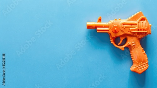 Orange toy gun on blue background photo
