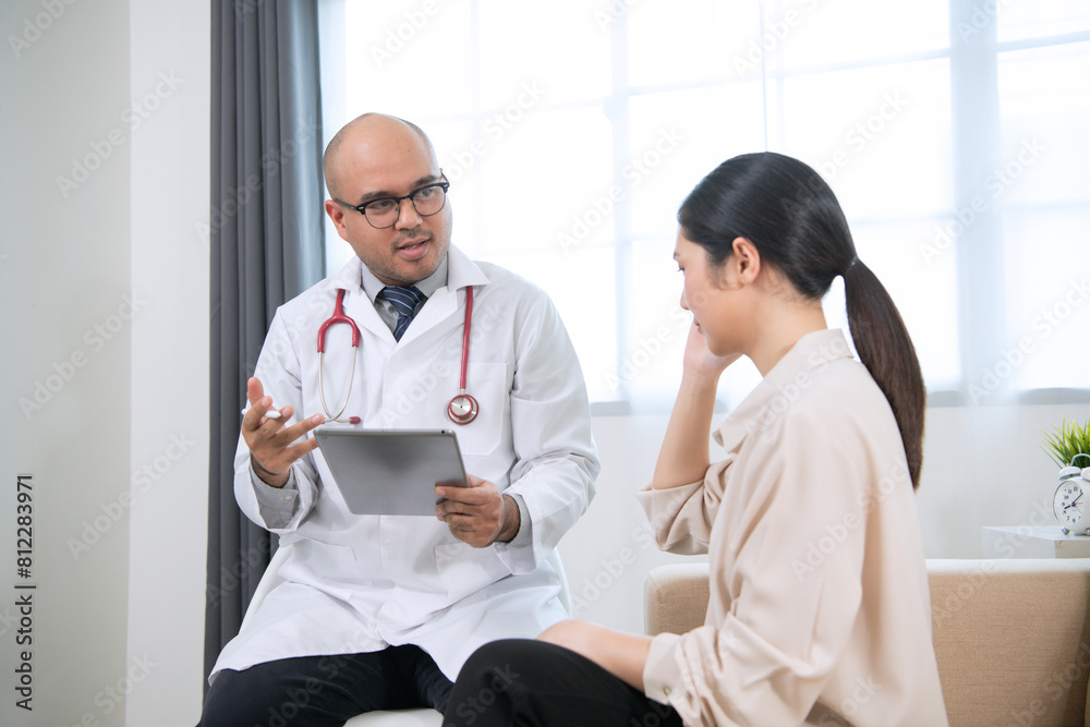 Foreign tanned male doctor in white medical clothes discussing woman's illness male doctor opens an iPad, shows treatment and medication information, and provides information of each drug.