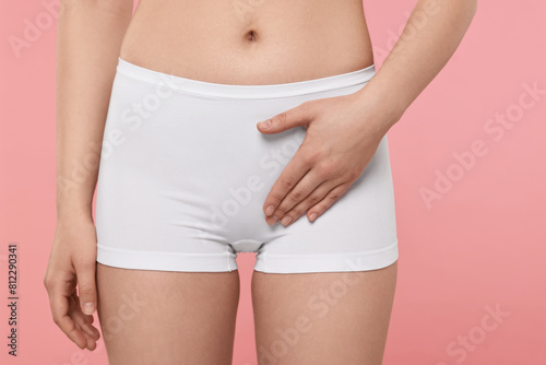 Woman holding hand near panties on pink background, closeup. Women's health © New Africa