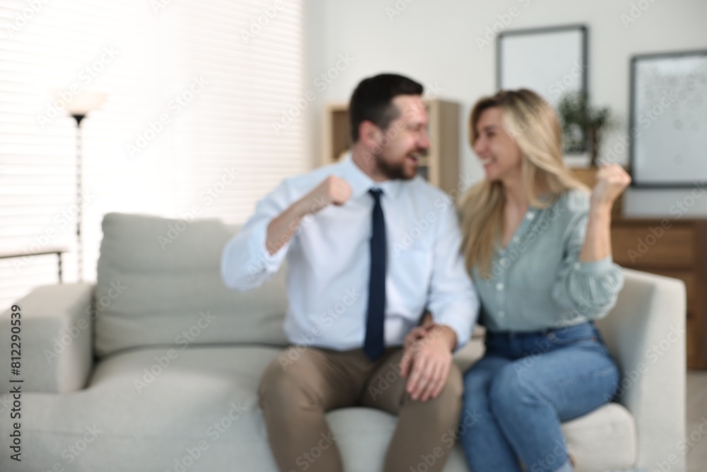 Blurred view of happy couple sitting on sofa at home, space for text Blurred view of happy couple sitting on sofa at home, space for text