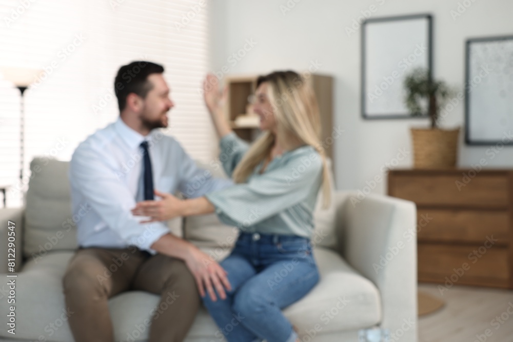 Blurred view of happy couple sitting on sofa at home Blurred view of happy couple sitting on sofa at home