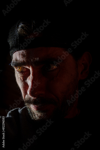 hombre con mirada tenebrosa con ojos brillantes en fondo negro oscuro  photo