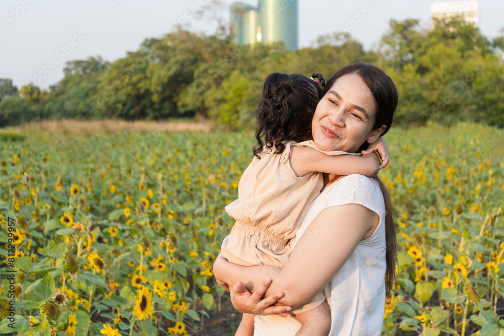 Mother and daughter hugging in the evening sunflower field.