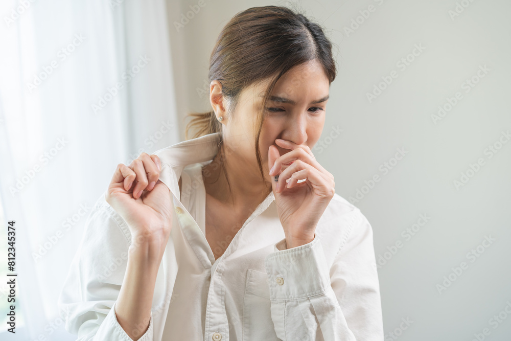 Bad smell nose concept asian young housewife woman having smelling clothes her shirt collar, sniff smelly dirty stinky musty, look disgusting from clothes after washed, laundry out of machine at home. Bad smell nose concept asian young housewife woman having smelling clothes her shirt collar, sniff smelly dirty stinky musty, look disgusting from clothes after washed, laundry out of machine at home.
