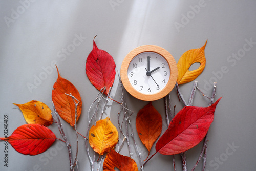 Daylight Saving Time concept background. 
Fall Back decoration colorful leaves and clock composition on gray background.  photo