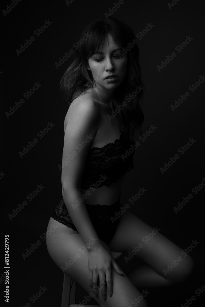 Studio portrait of a beautiful caucasian woman in her thirties wearing black lace underwear and top. Her long dark hair is blowing in the wind. This is a moody portrait. 