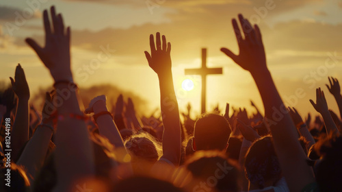 A crowd of people raising their hands in worship towards a cross at sunset. This image captures the essence of faith, unity, and spiritual devotion, highlighting the collective celebration and reveren photo