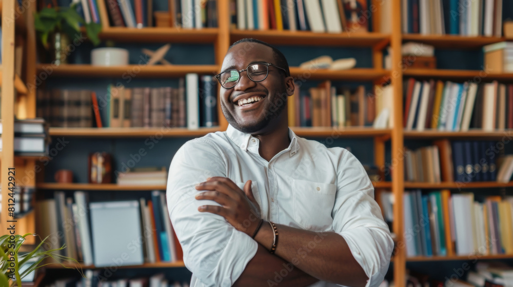Happy African American Man in Casual Style with Glasses Laughing in a Library. Smiling Academic Surrounded by Books and Shelves in a Bright and Modern Study Space. Happy African American Man in Casual Style with Glasses Laughing in a Library. Smiling Academic Surrounded by Books and Shelves in a Bright and Modern Study Space.