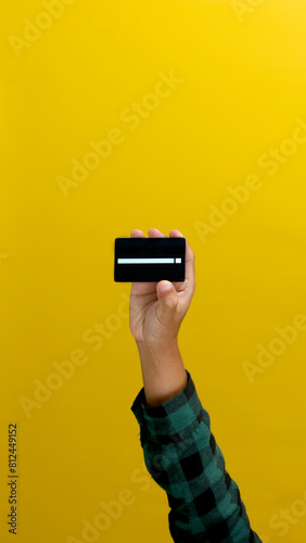 Hand holding Bank credit card isolated on yellow background
