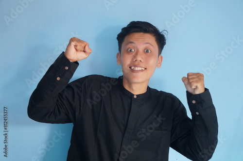 portrait of smiling happy asian young man with clenched fists