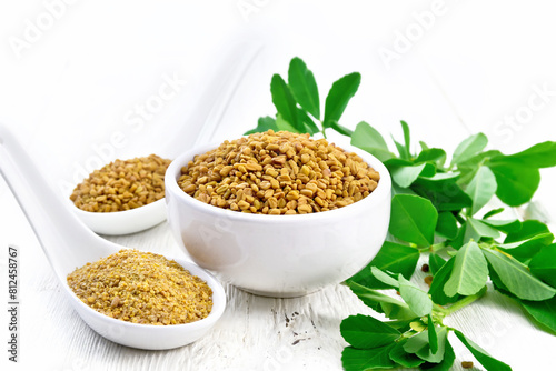 Fenugreek in bowl and two spoons with leaves on board