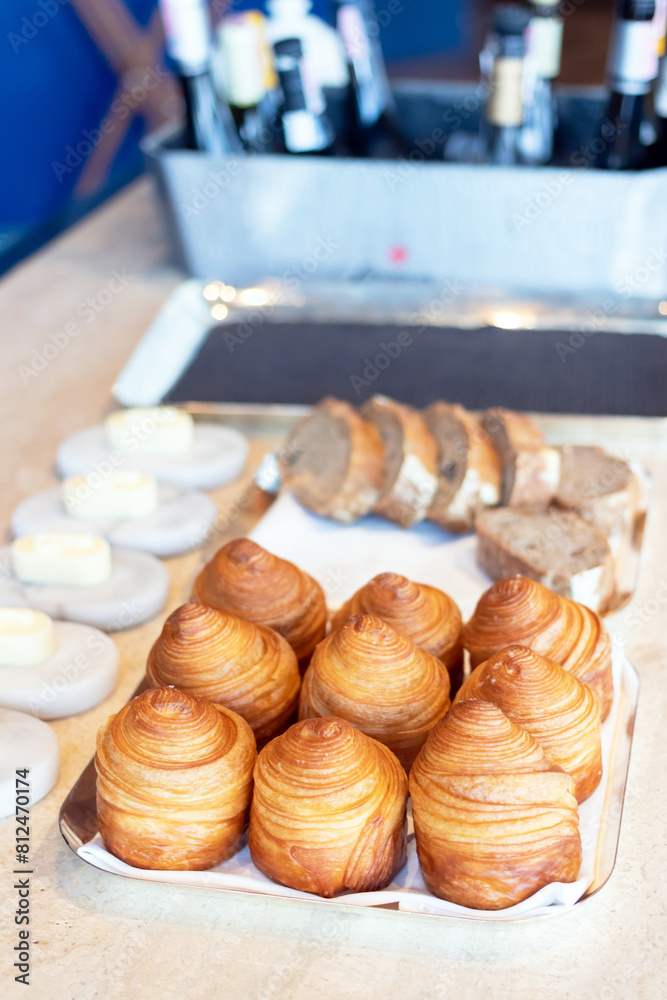Freshly baked croissants on a white plate with butter and jam on a wooden table.