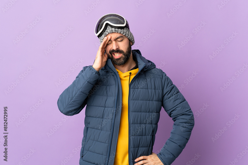 Skier man with snowboarding glasses over isolated purple background with headache Skier man with snowboarding glasses over isolated purple background with headache