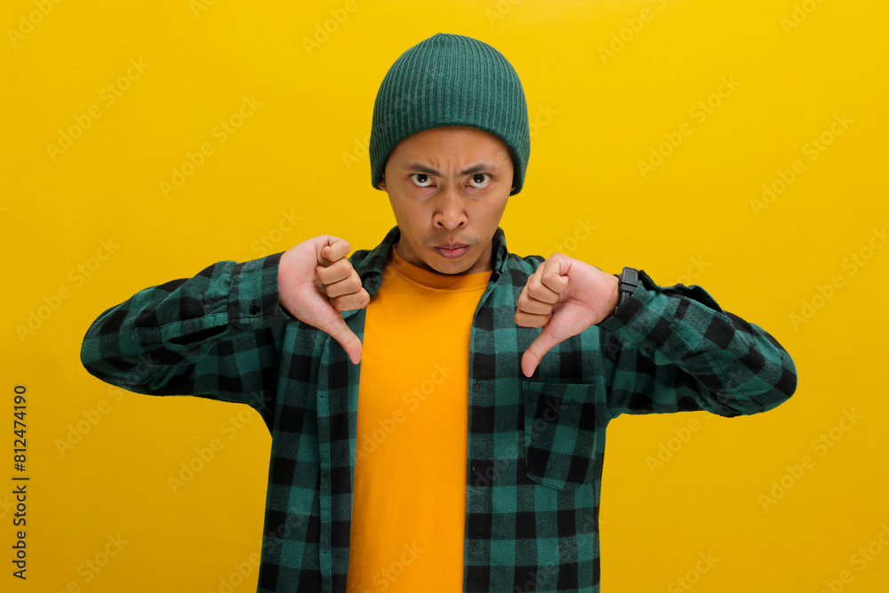 A dissatisfied young Asian man, dressed in a beanie hat and casual shirt, is expressing disappointment by giving a thumbs down gesture, indicating a negative review or dislike towards something A dissatisfied young Asian man, dressed in a beanie hat and casual shirt, is expressing disappointment by giving a thumbs down gesture, indicating a negative review or dislike towards something