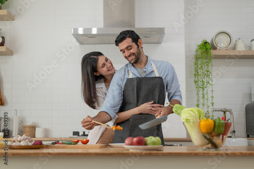 Happy couple in love cooking in the kitchen at home and hugging