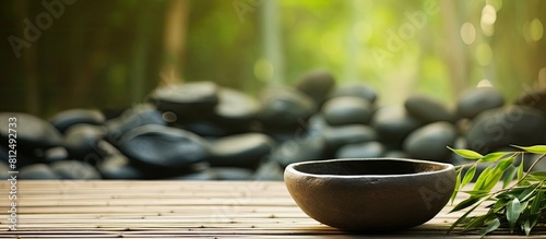 Bowl filled with stones surrounded by bamboo grove on mat background copy space image