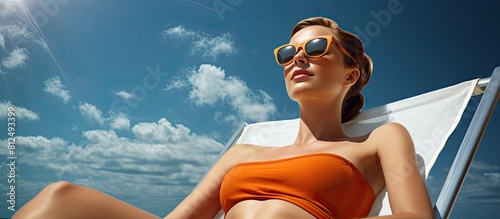 A girl with glasses rests on a beach chaise lounge with a copy space image in the background