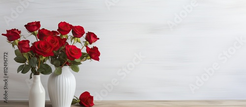 Fototapeta Naklejka Na Ścianę i Meble -  A copy space image featuring a vase of red roses set against a whitewashed wooden wall