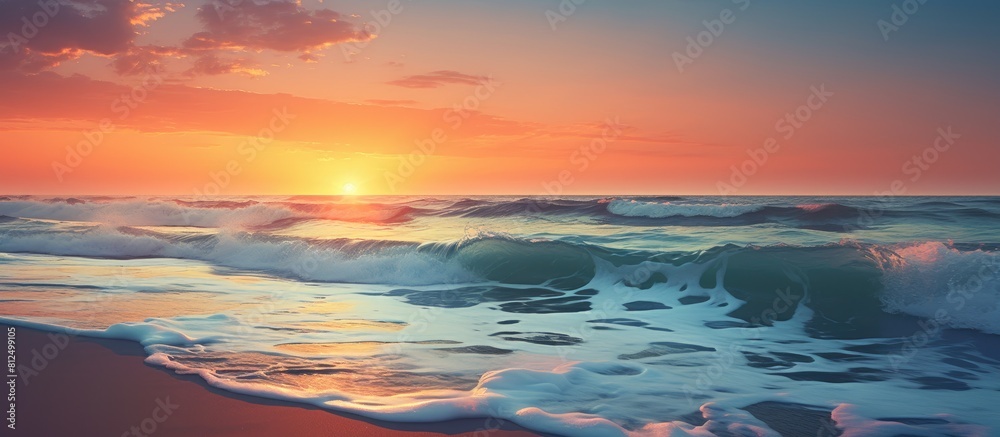 Copy space image of a stunning sunset and the crashing waves of the sea against a sandy beach
