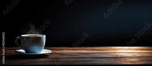 A coffee cup sitting on a dark table with ample space for placing images