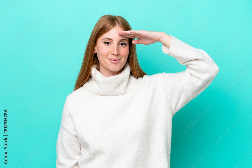Young redhead woman isolated on blue background saluting with hand with happy expression Young redhead woman isolated on blue background saluting with hand with happy expression