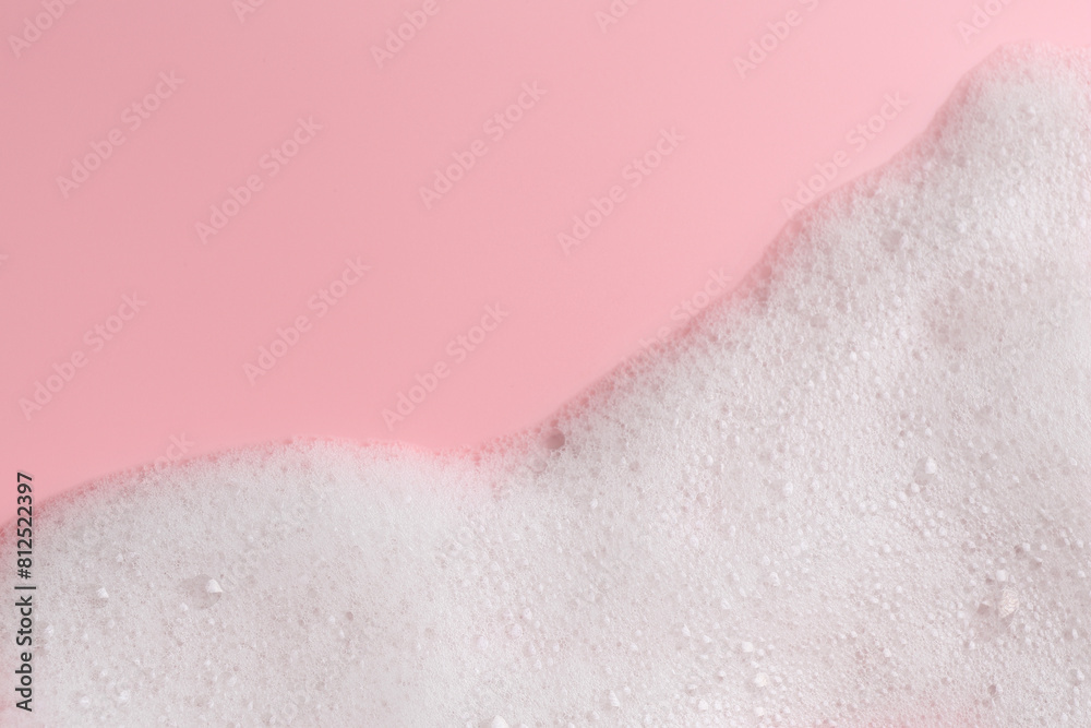 Fototapeta premium White fluffy foam on pink background, top view. Space for text