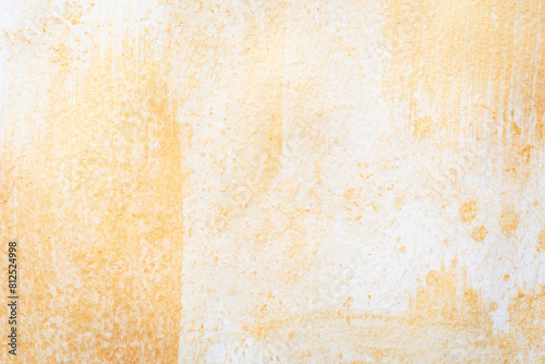 Golden paint creates an abstract pattern on a textured white paper surface. Golden glitter background